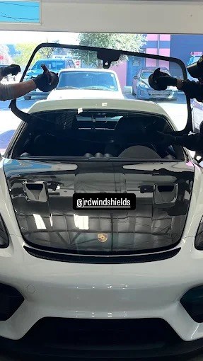 JRD technician setting a new windshield into a Porsche 911 at the Round Rock auto glass shop